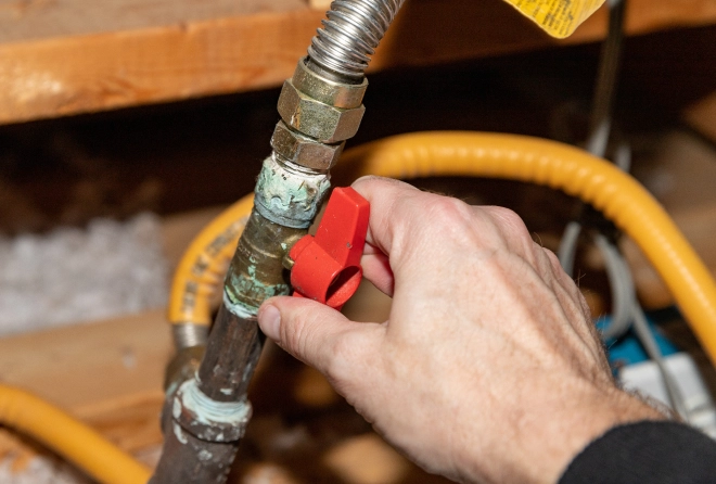 A hand reaches and turns a knob on a gas line in an Austin, Texas home.